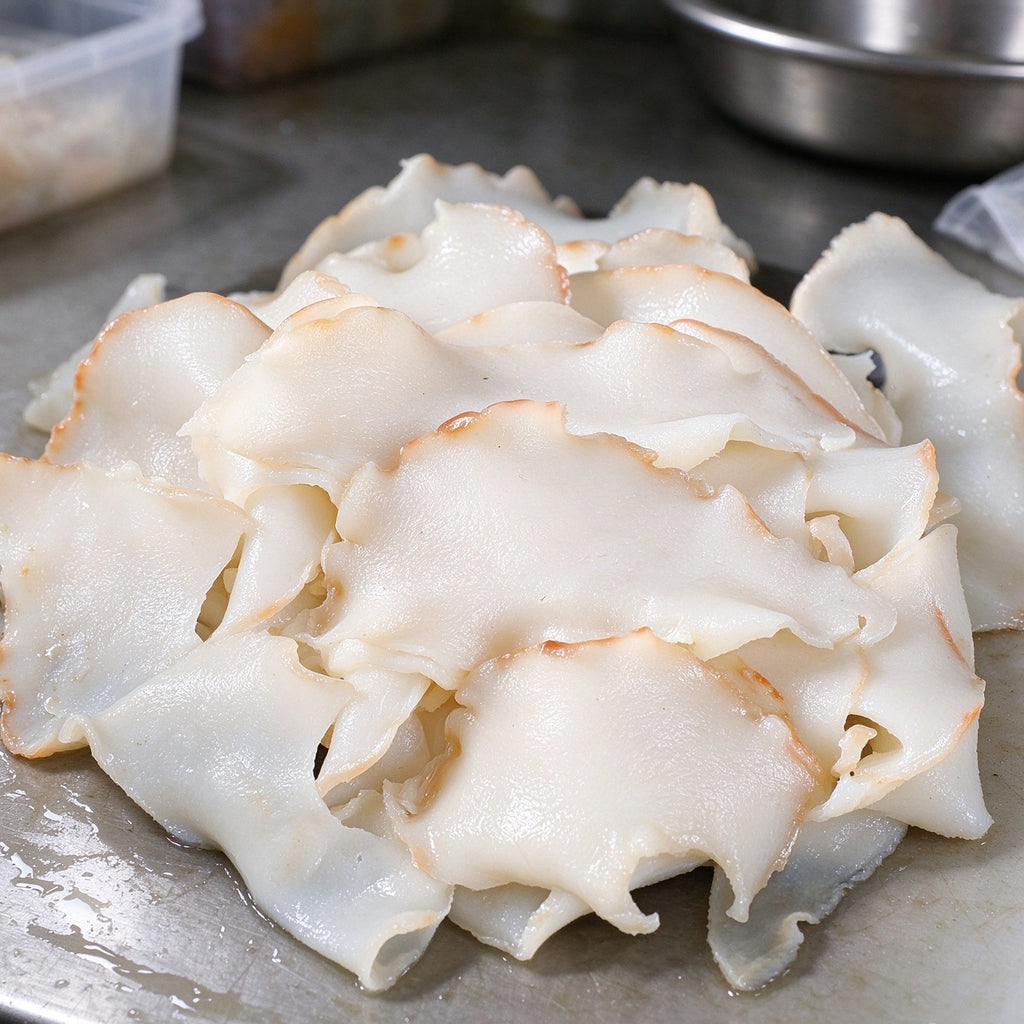 Thin white slices of conch meat with a golden rim