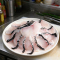 Boneless snakehead fillets with dark skin edge on a white plate